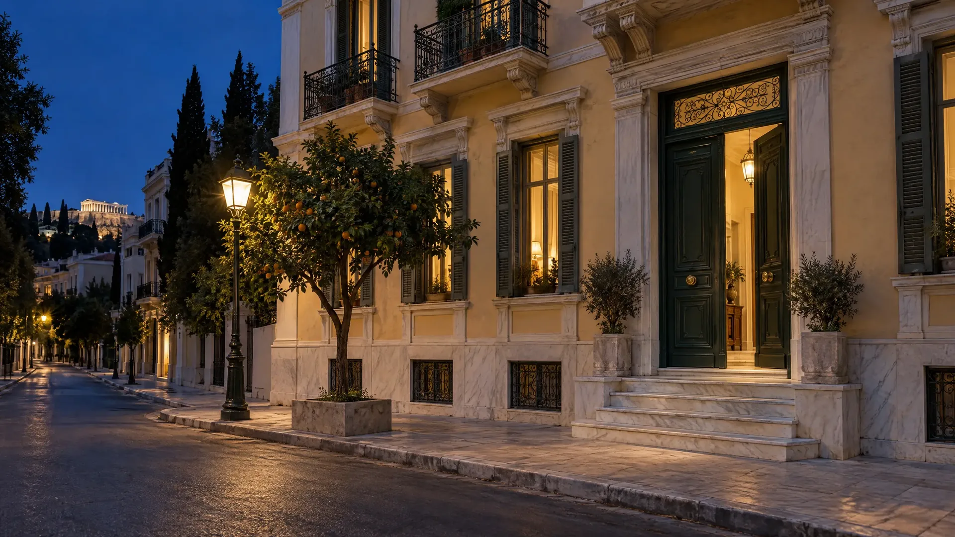 The lit front door of a neoclassical building on a quiet street in central Athens at dusk
